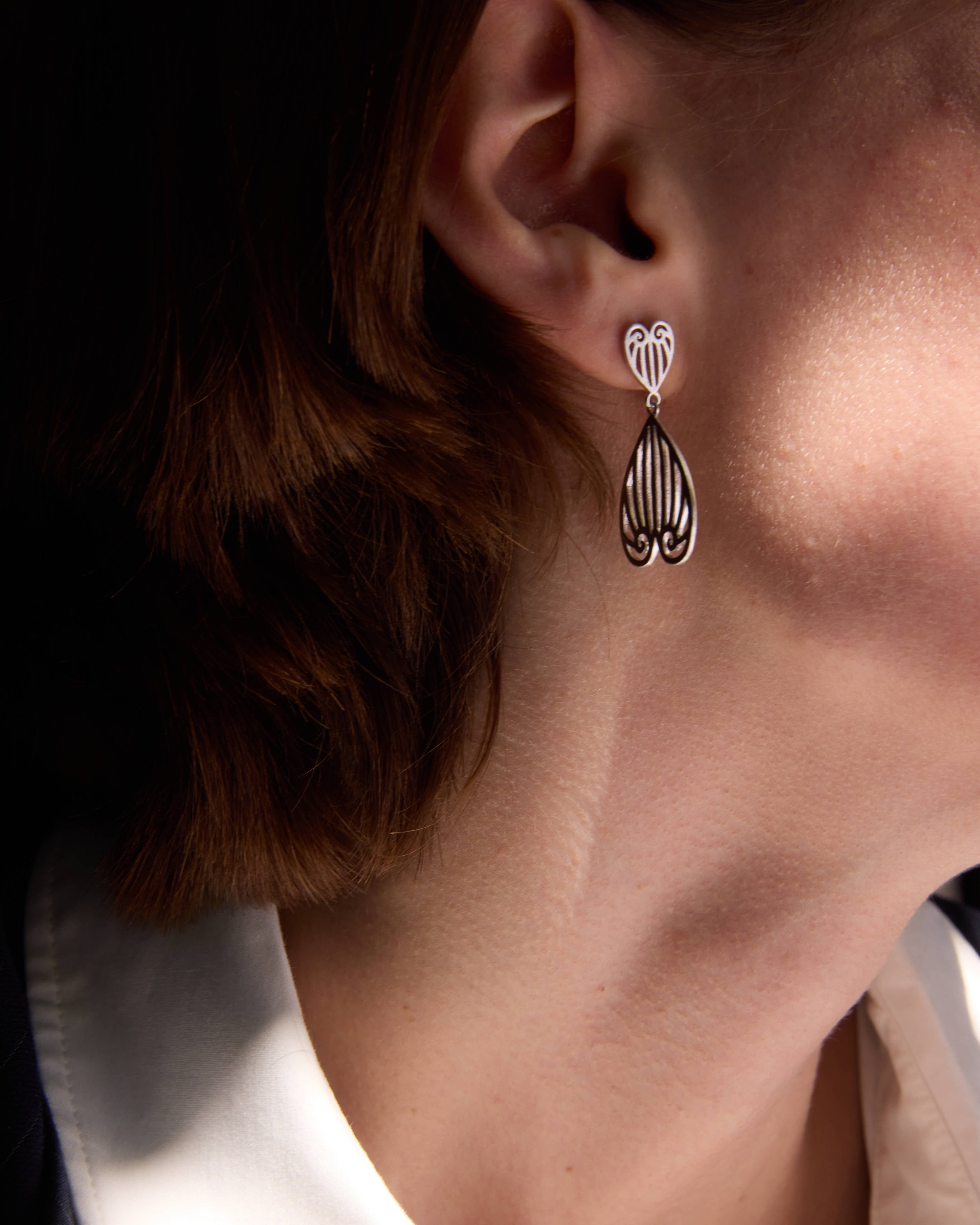 Celestes Jewelry. Close-up of an earring worn by a person with a neutral background