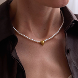 Pearl necklace with a gold heart pendant worn by a person, with 'Celestes Jewelry' branding.