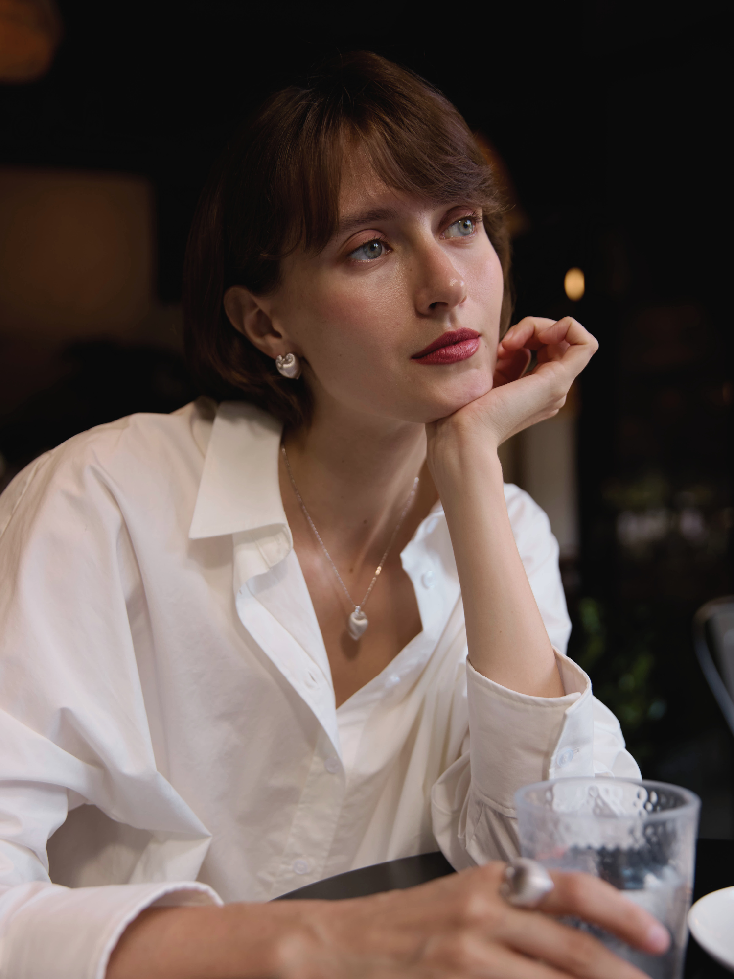 Woman in a white shirt holding a glass with a blurred background