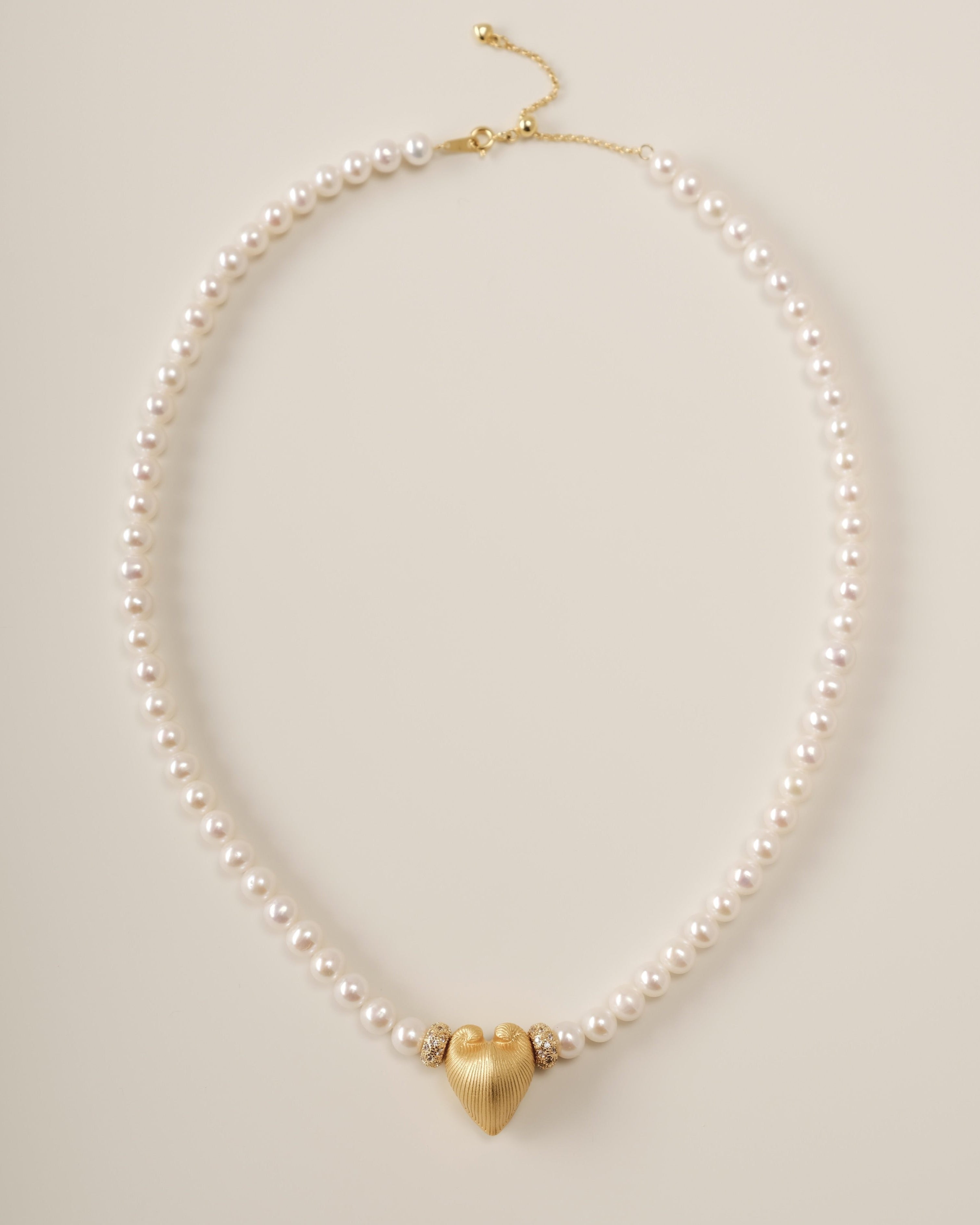 A celestial river of pearls and stardust, the Cœur Brillant Heart Pearl Necklace marries organic serenity with cosmic brilliance. Designed for those who seek elegance with a whisper of rebellion, this piece transforms the delicate balance of strength and softness into a wearable constellation.
Design & Craftsmanship:
Dual-Texture Heart Pendant: The focal 15.6*18.8mm Meiocardia vulgaris heart, crafted in S925 silver and plated in 18k white gold, shifts from rugged, shell-inspired edges to a polished heart si