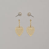 Gold heart-shaped earrings on a gray background