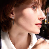 Close-up of a woman wearing earrings and a bracelet, with a blurred background