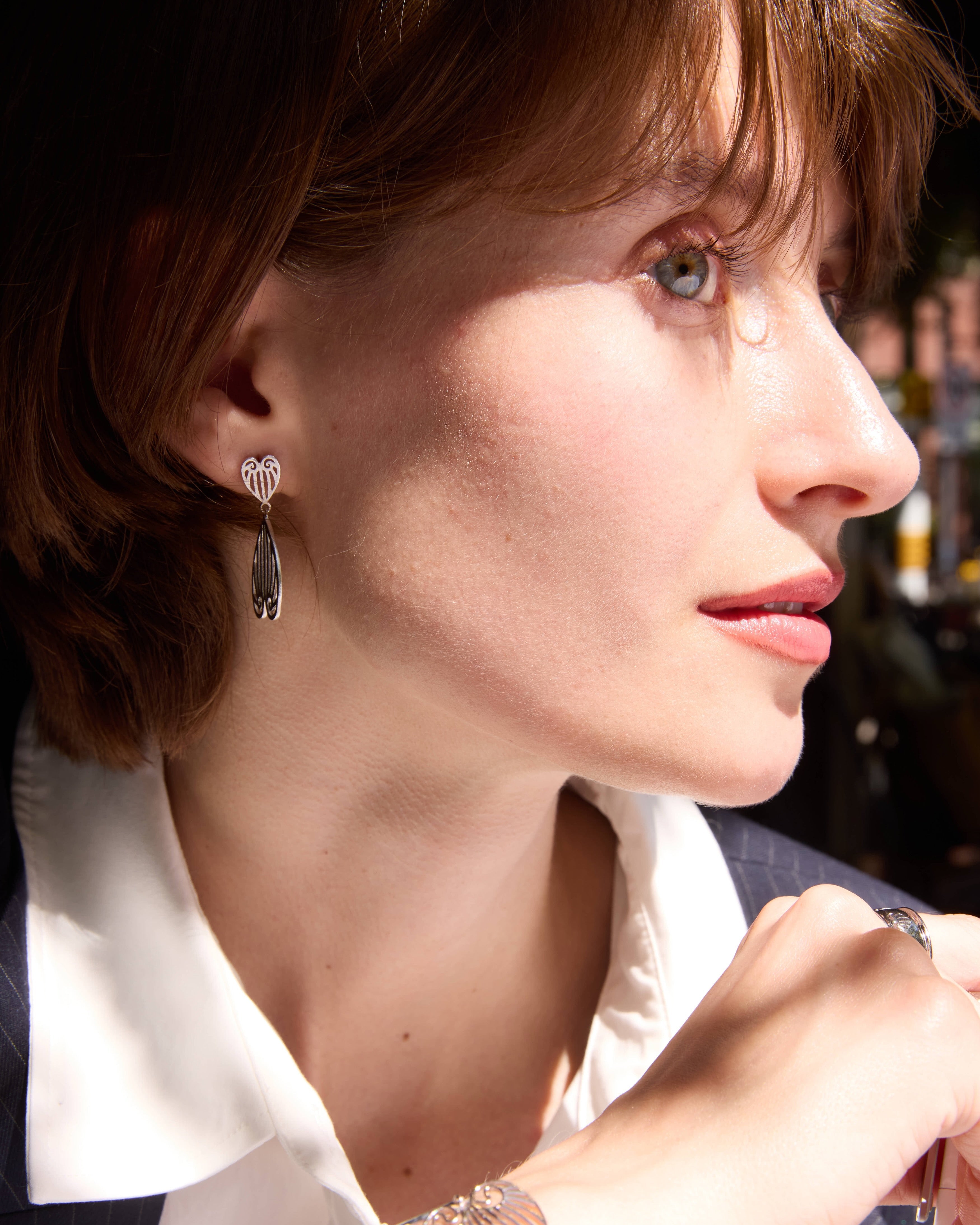 Close-up of a woman wearing earrings and a bracelet, with a blurred background