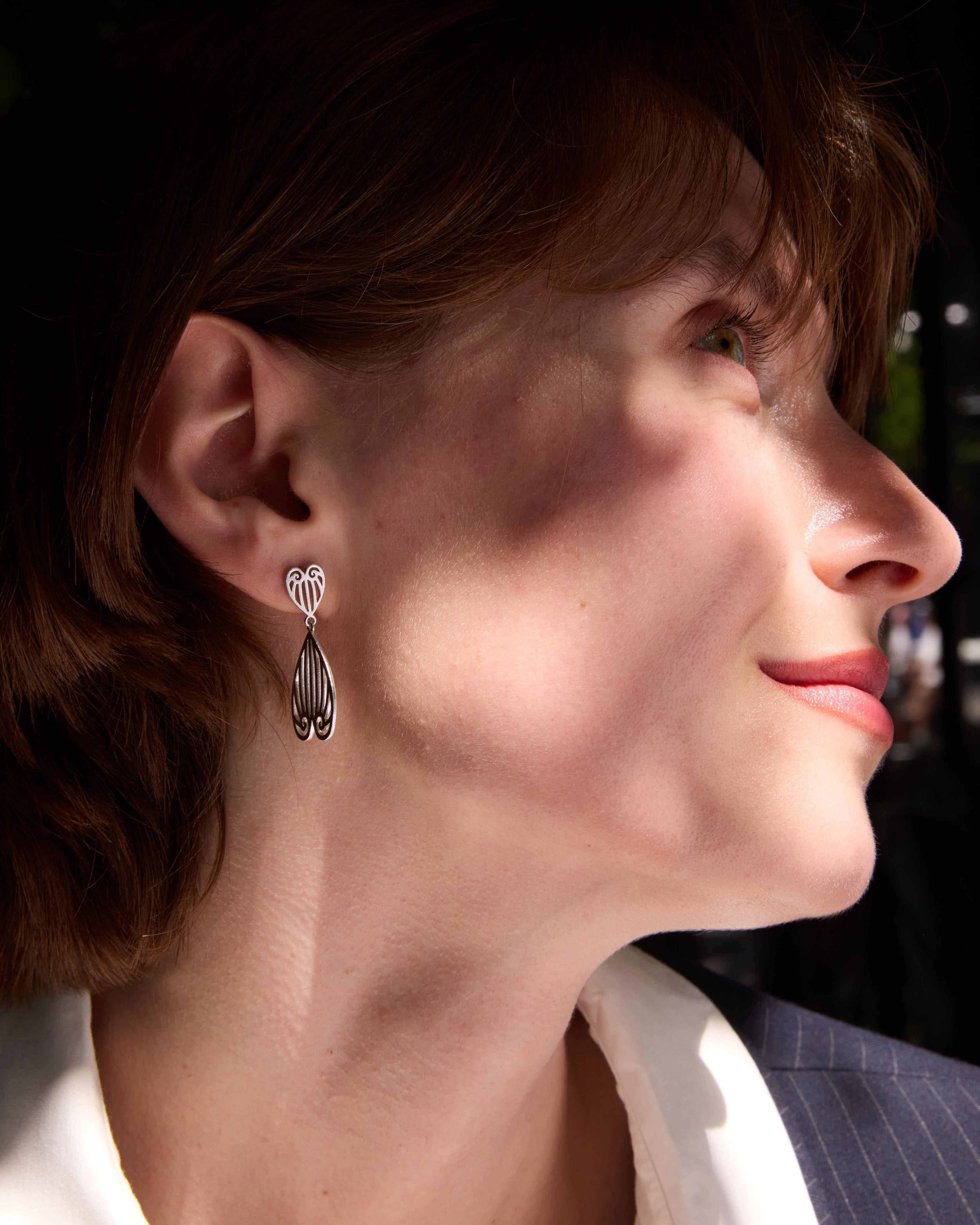 Close-up of a woman wearing silver earrings with a blurred background
