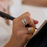 Hand holding a pen with heart rings on a blurred background