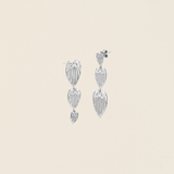 Pair of silver leaf-shaped earrings on a beige background
