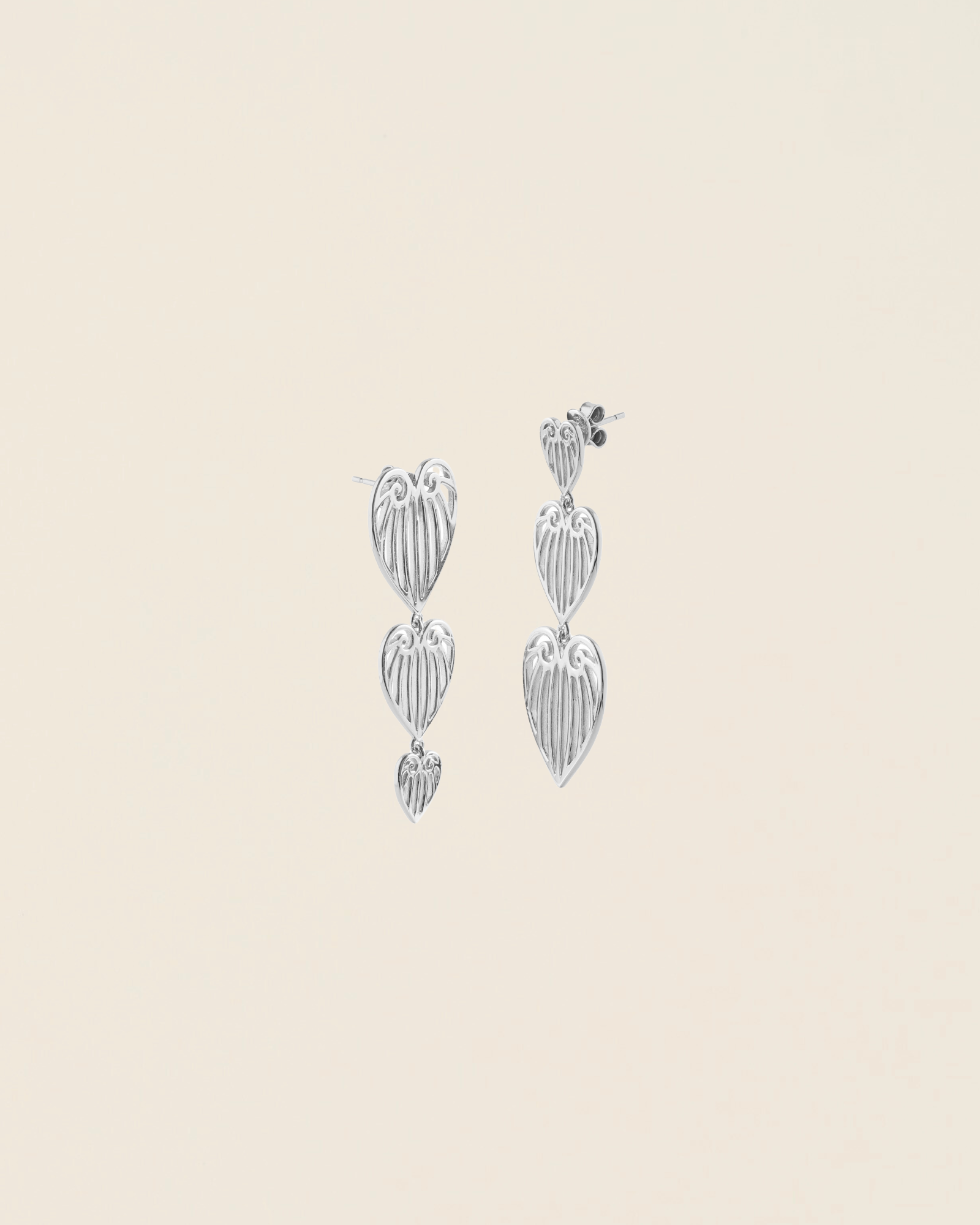 Pair of silver leaf-shaped earrings on a beige background