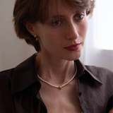 Woman wearing a necklace with a plain background, featuring the brand 'Celestes Jewelry'.