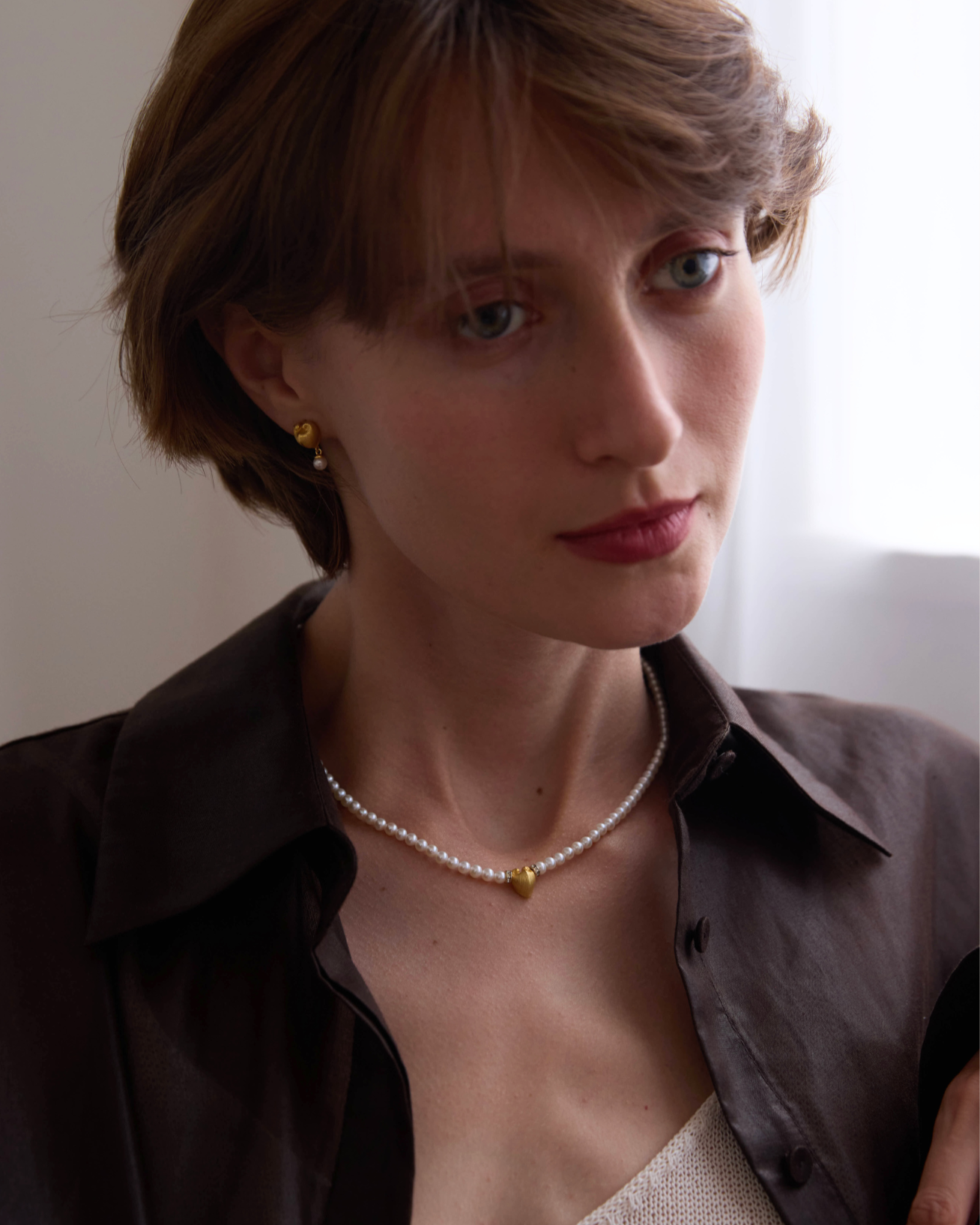 Woman wearing a necklace with a plain background, featuring the brand 'Celestes Jewelry'.