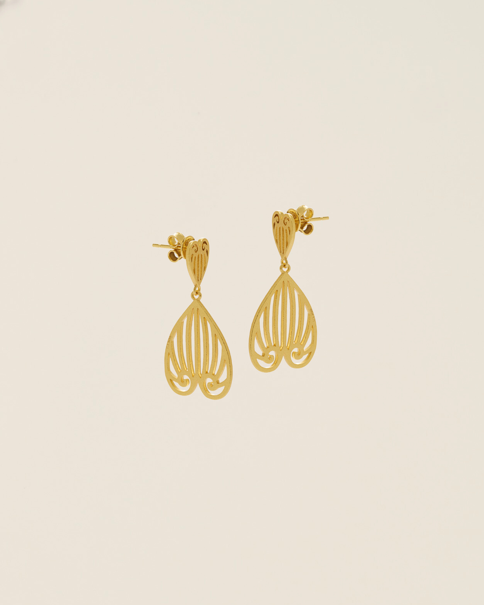 Gold earrings on a beige background