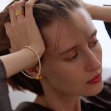 Woman wearing gold jewelry with a neutral background