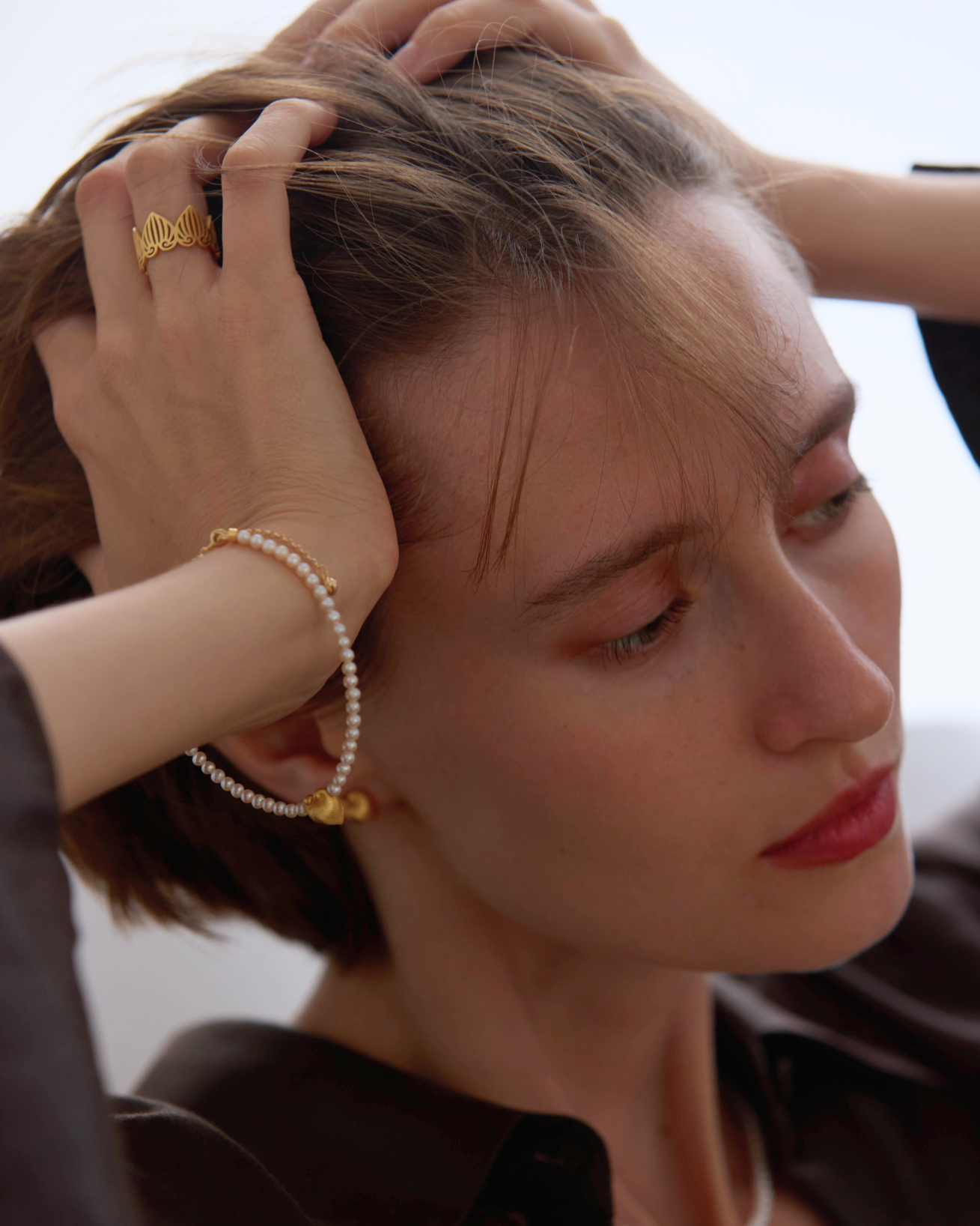 Woman wearing gold jewelry with a neutral background