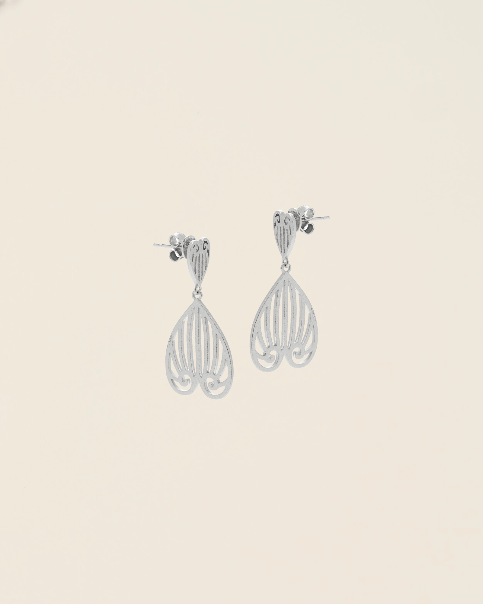 Celestes jewelry Pair of silver earrings on a beige background