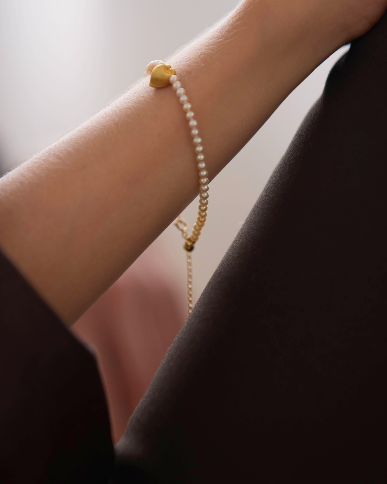 Pearl bracelet on a wrist with a blurred background, featuring the brand 'Celestes Jewelry'.
