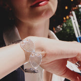 celestes jewelry Close-up of a person wearing a silver bracelet with a heart design.