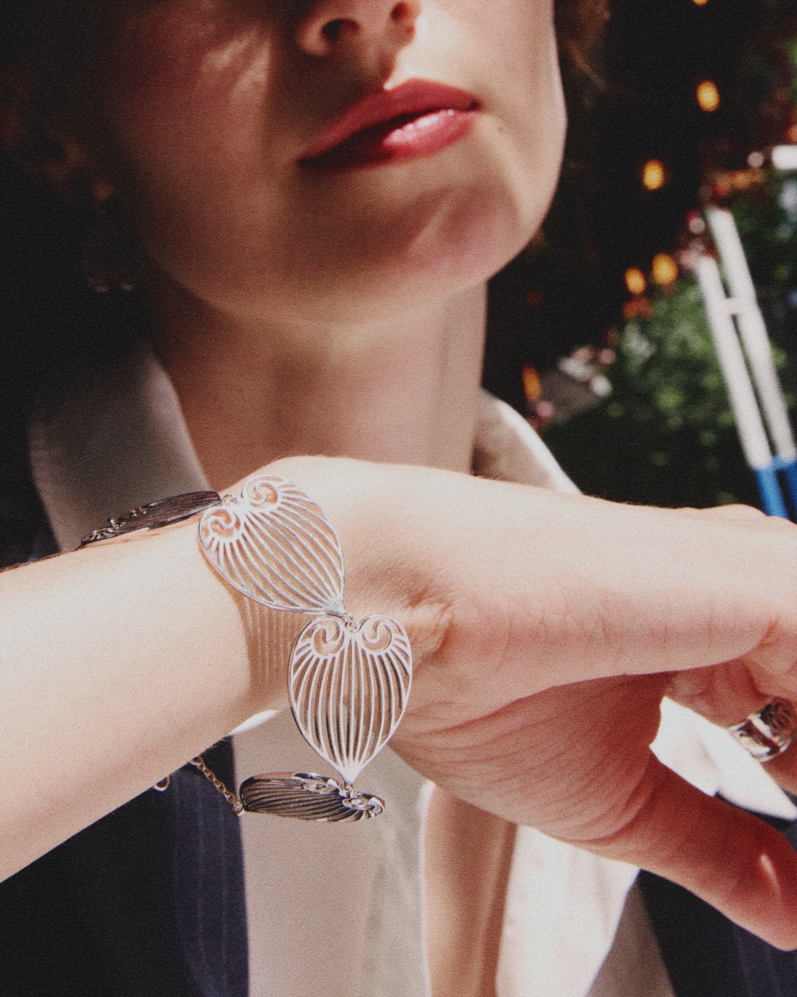 celestes jewelry Close-up of a person wearing a silver bracelet with a heart design.