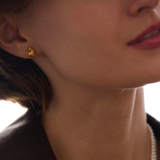Close-up of a woman wearing gold earrings with 'Célestes Jewelry' branding.