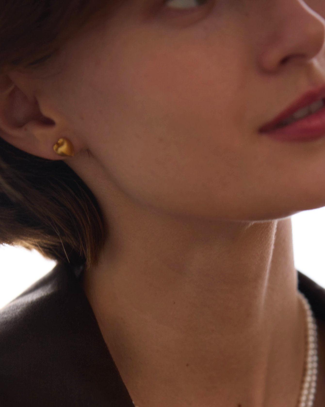 Close-up of a woman wearing gold earrings with 'Célestes Jewelry' branding.