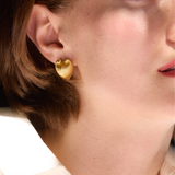 Close-up of a person wearing gold hoop earrings with a blurred background