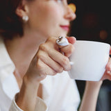 Woman holding a white mug in a silver heart ring