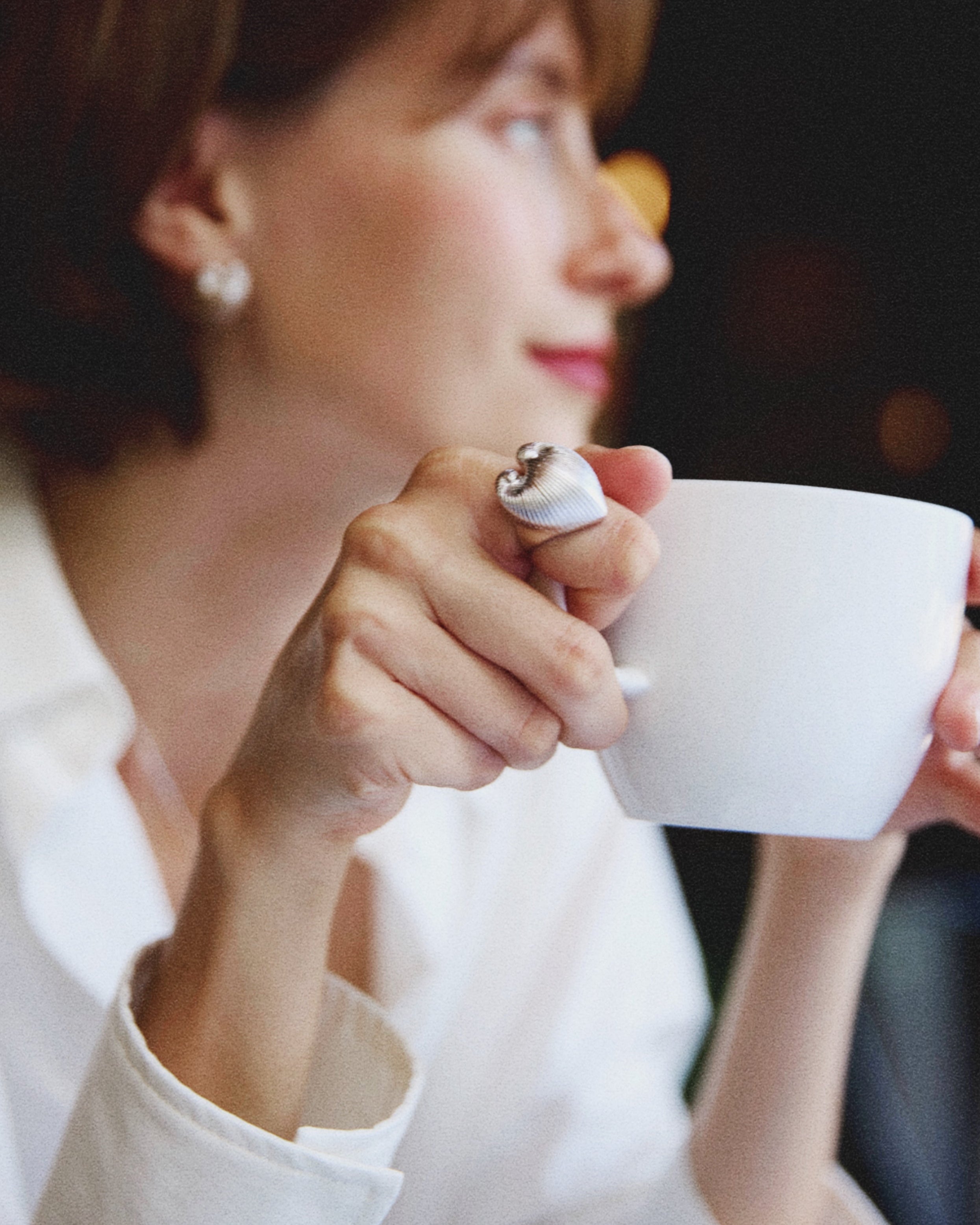 Woman holding a white mug in a silver heart ring