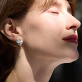 Close-up of a person wearing heart-shaped earrings with a blurred background