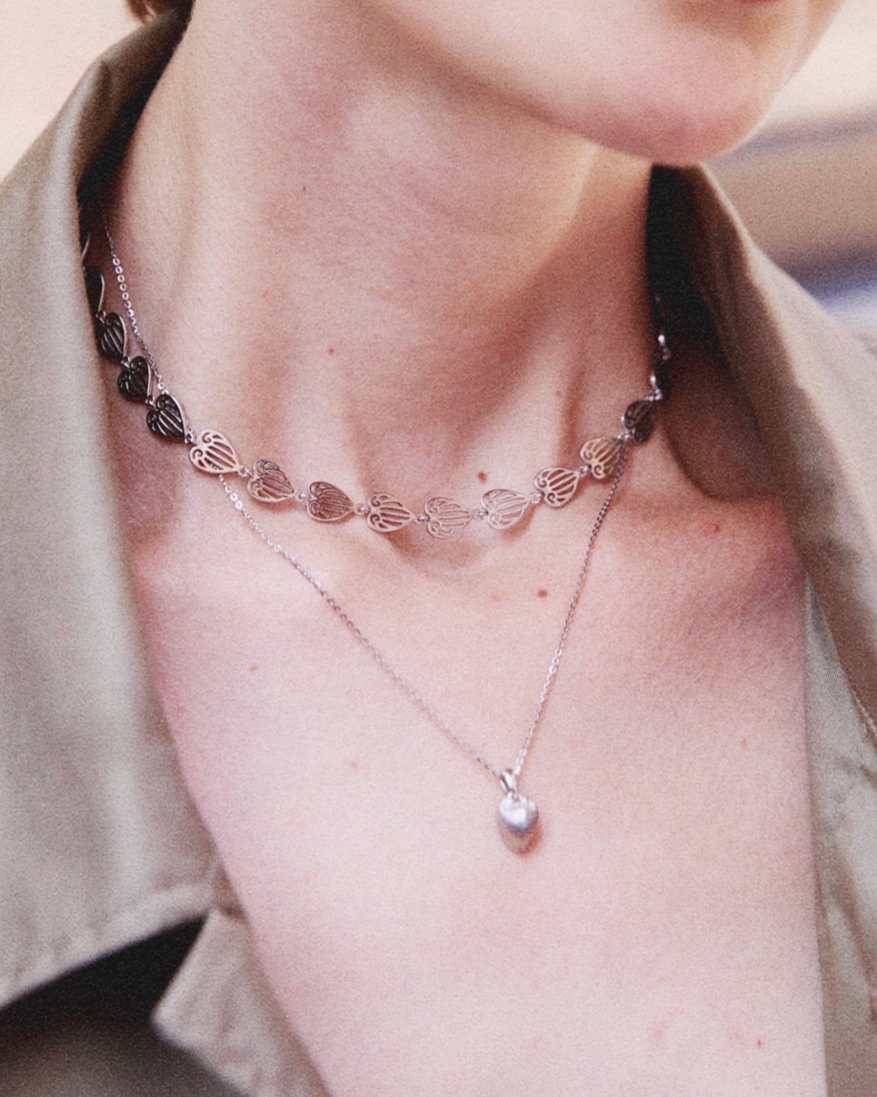 Close-up of a person wearing a necklace with a pendant.