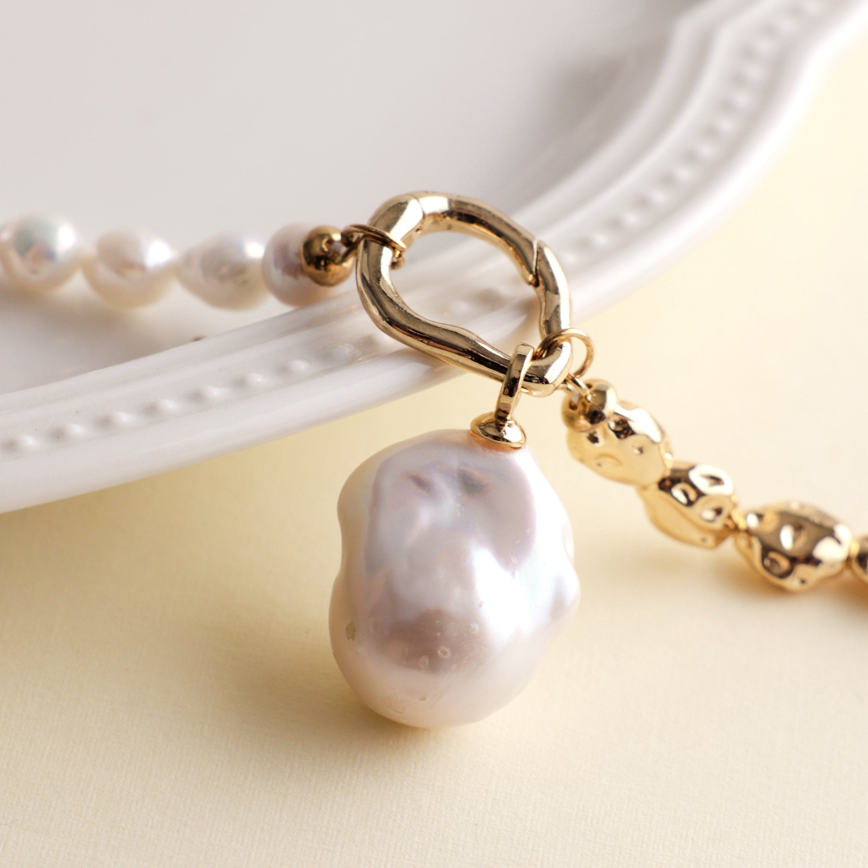 Embrace the beauty of asymmetry with this stunning Baroque freshwater pearl necklace. Featuring a lustrous Baroque pearl pendant, this piece stands out with its natural glow and unique shape. The pendant is detachable, allowing you to add it to other necklaces for a customized look. The chain and accents are crafted from 18k gold-filled materials, ensuring long-lasting color and a beautiful shine that complements the pearls.