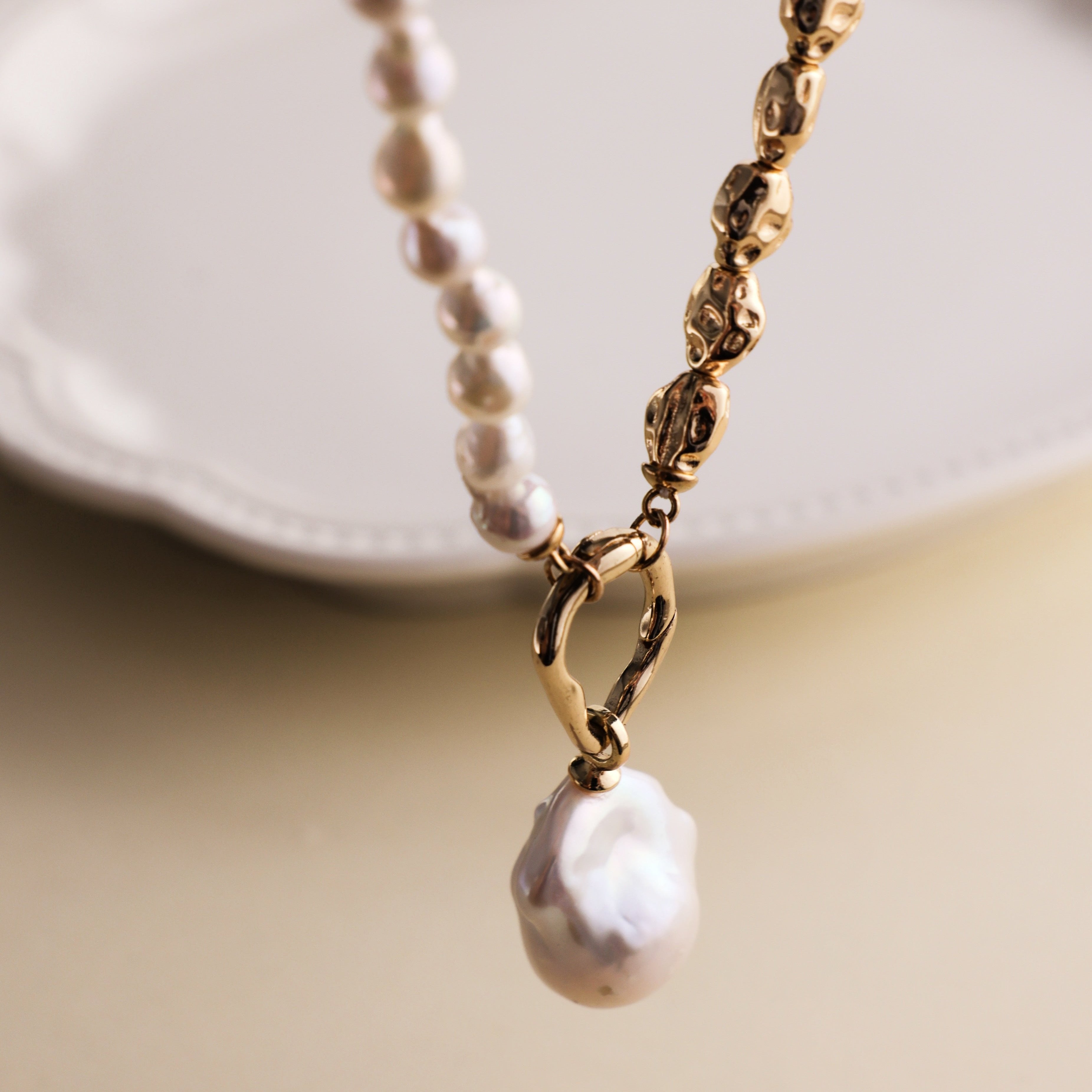 Embrace the beauty of asymmetry with this stunning Baroque freshwater pearl necklace. Featuring a lustrous Baroque pearl pendant, this piece stands out with its natural glow and unique shape. The pendant is detachable, allowing you to add it to other necklaces for a customized look. The chain and accents are crafted from 18k gold-filled materials, ensuring long-lasting color and a beautiful shine that complements the pearls.