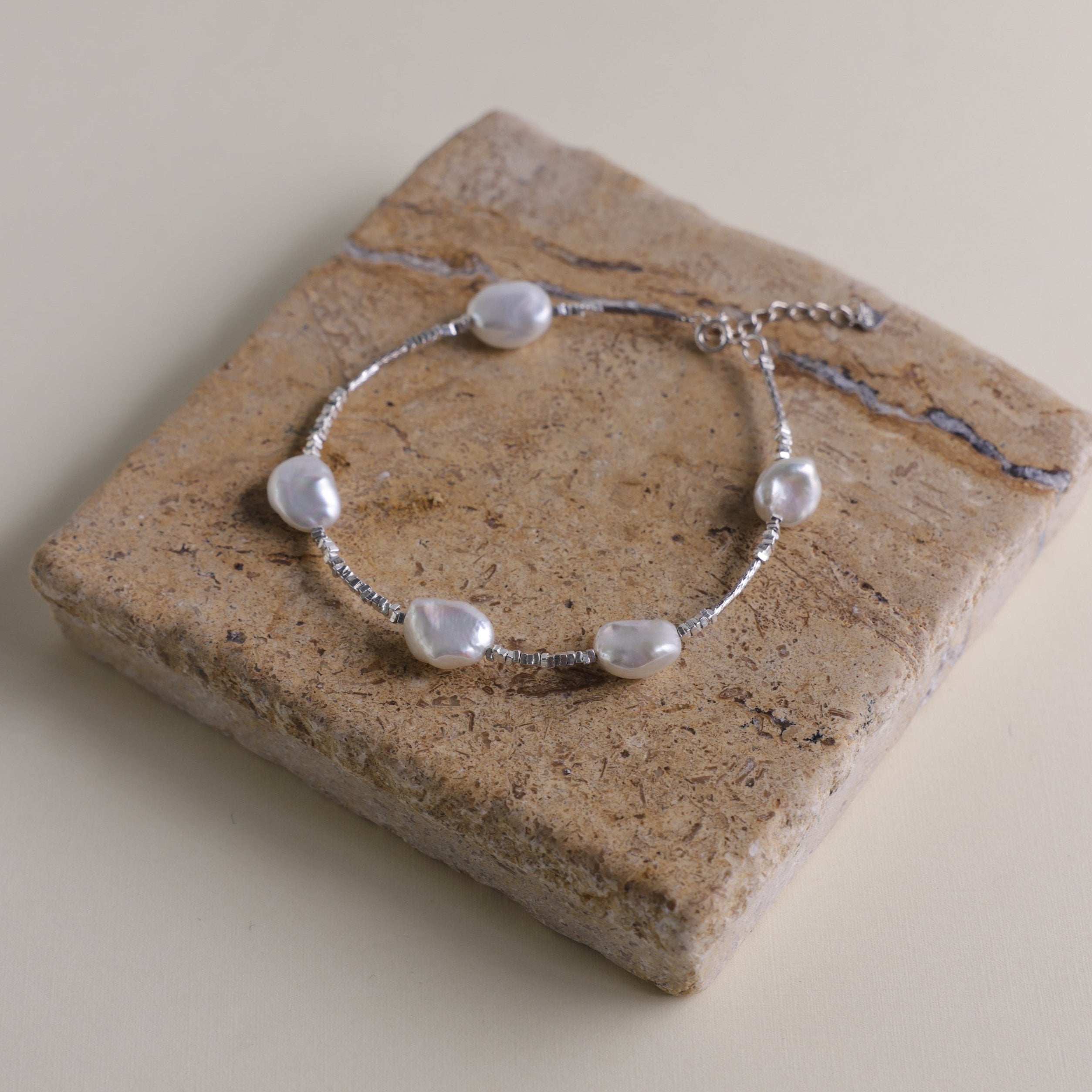 Materials:
- Pearls: Five lustrous Keshi pearls, each about 10mm long.
- Metal: High-quality 925 Sterling Silver for all hardware and detailing.
- Length: The bracelet measures 18.5 cm, featuring an adjustable chain for a customized fit.
Design Highlights: 
This piece is skillfully crafted, showcasing a minimalist yet striking design. The irregularity of the Keshi pearls provides a modern twist on a classic bracelet, complemented by delicate sterling silver accents that add a refined touch.
Styling Tips:
- 
