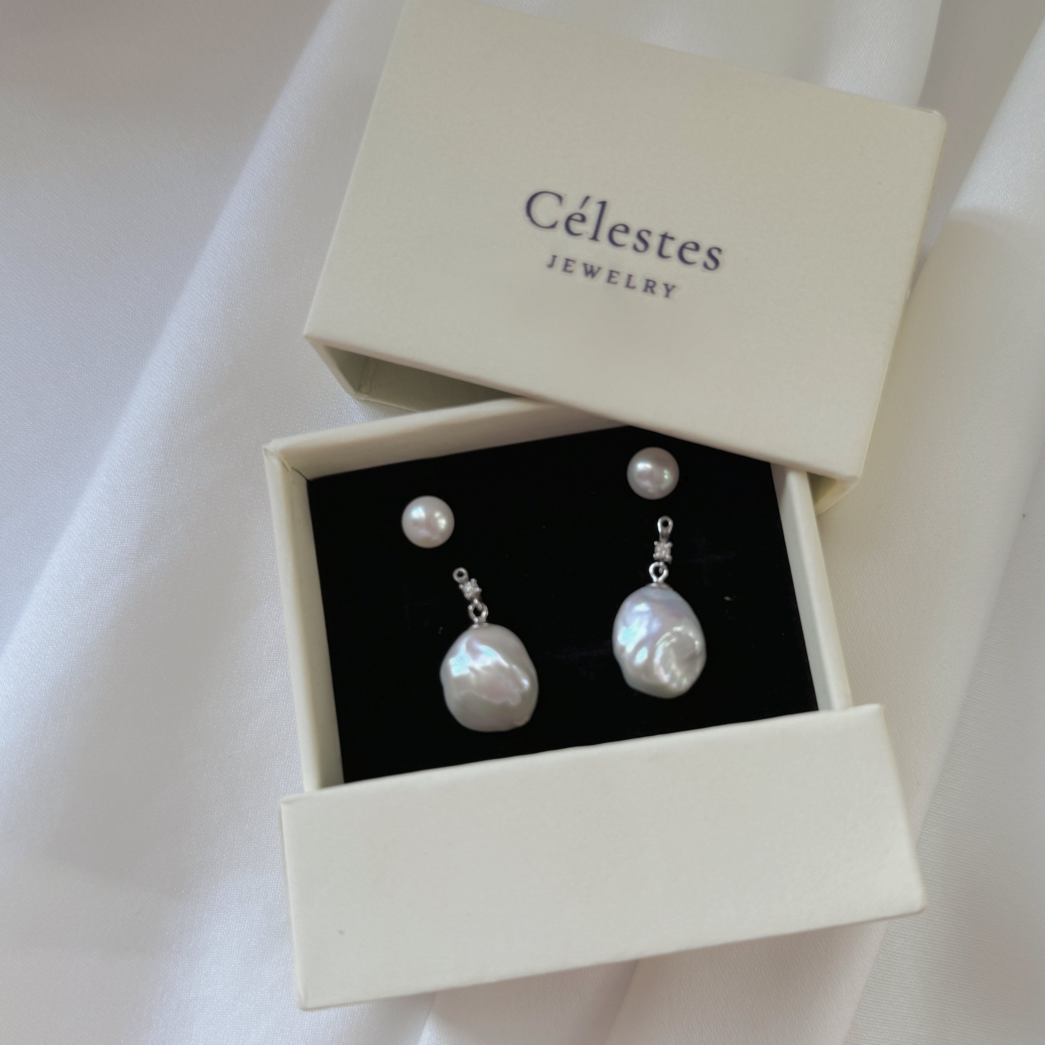 These earrings feature a detachable design that allows you to wear the round pearl with zircon accents for a minimalist look, or add the Keshi pearl for a more dramatic effect. The unique combination of differently shaped pearls with sterling silver and zircon detailing creates a stunning visual contrast, while the versatility of the design makes these earrings a must-have addition to any jewelry collection.
Materials:
- Pearls: One 10mm Keshi pearl and one 6-7mm round pearl on each earring.
- Metal: All co
