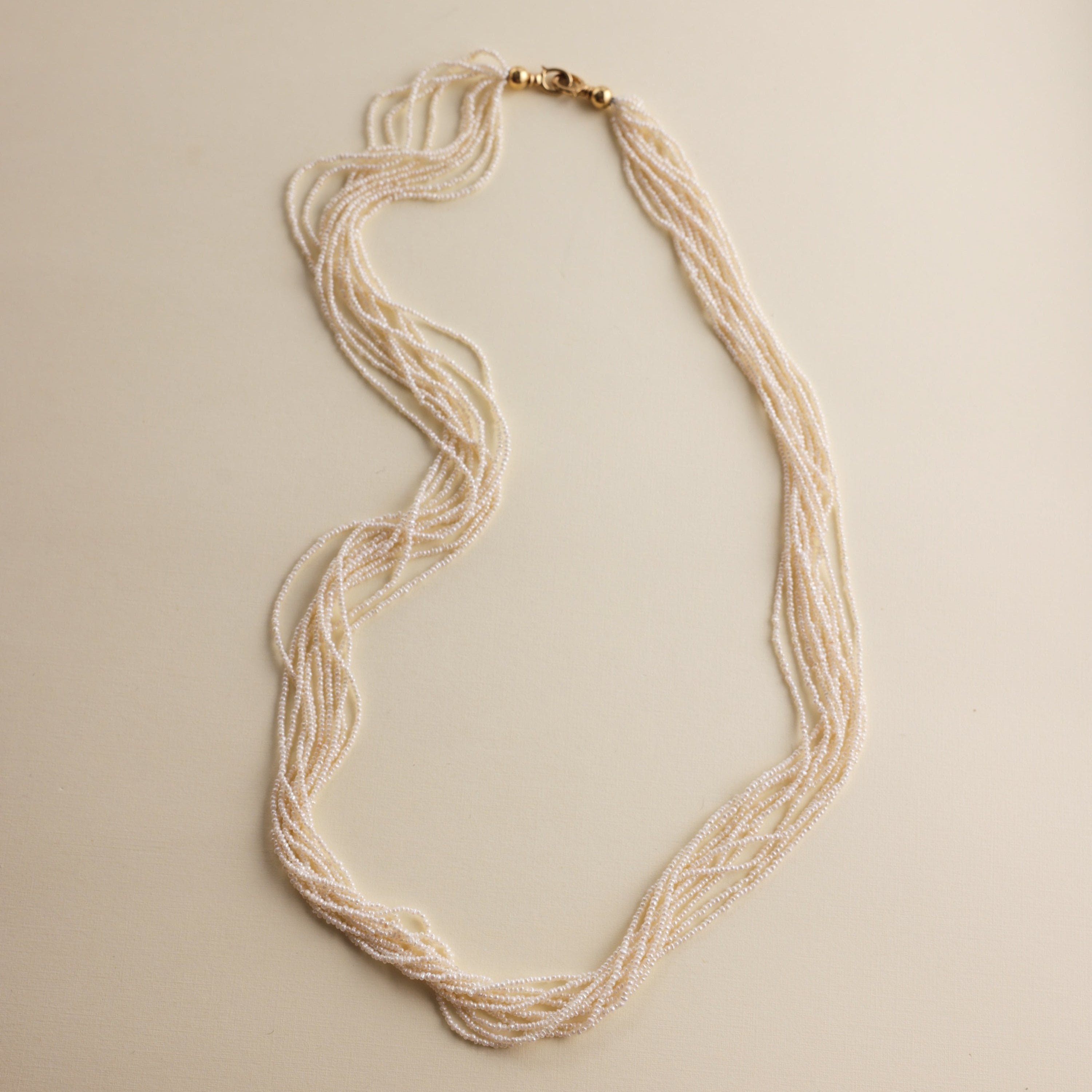 This extraordinary necklace is crafted from thousands of the world's smallest Akoya saltwater pearls, delicately hand-strung into 10 graceful strands. Each pearl measures just 1.0-1.5mm in size, a true testament to the incredible craftsmanship required to create such a piece. The process of drilling these baby pearls is so precise that nearly 1/3 of the pearls are lost, making this necklace an exceptionally rare and luxurious creation. These pearls are the type you’d expect to see in high couture jewelry, r