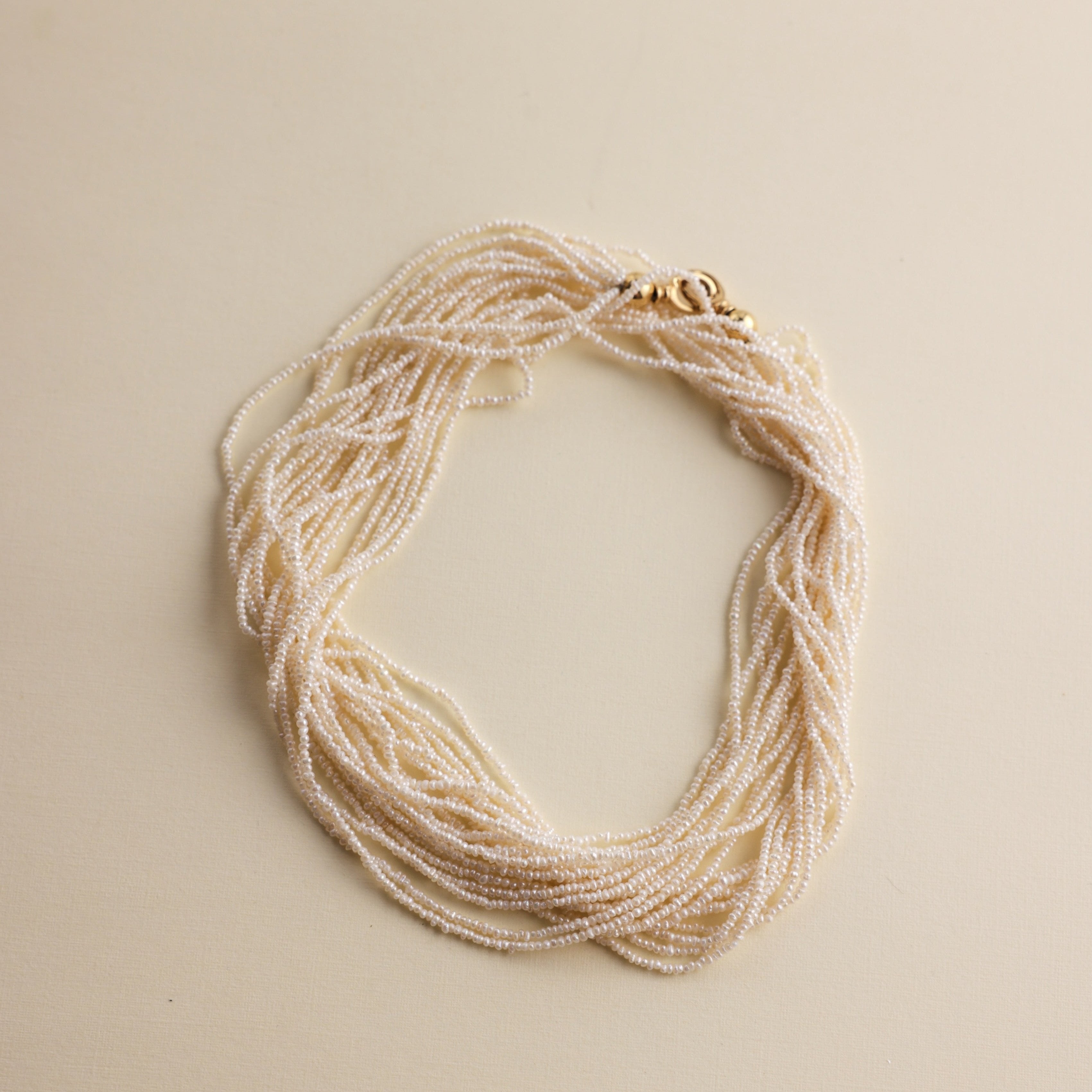 This extraordinary necklace is crafted from thousands of the world's smallest Akoya saltwater pearls, delicately hand-strung into 10 graceful strands. Each pearl measures just 1.0-1.5mm in size, a true testament to the incredible craftsmanship required to create such a piece. The process of drilling these baby pearls is so precise that nearly 1/3 of the pearls are lost, making this necklace an exceptionally rare and luxurious creation. These pearls are the type you’d expect to see in high couture jewelry, r