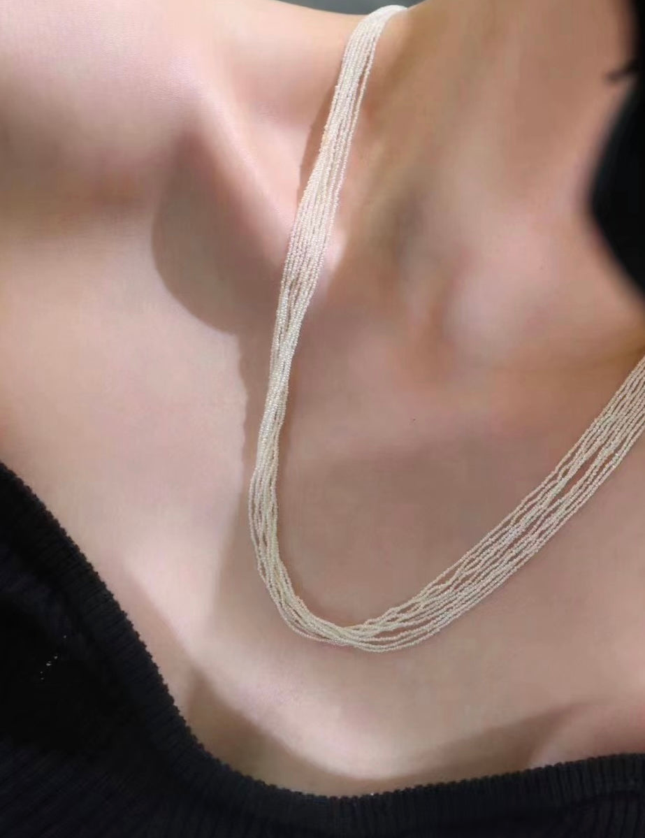 This extraordinary necklace is crafted from thousands of the world's smallest Akoya saltwater pearls, delicately hand-strung into 10 graceful strands. Each pearl measures just 1.0-1.5mm in size, a true testament to the incredible craftsmanship required to create such a piece. The process of drilling these baby pearls is so precise that nearly 1/3 of the pearls are lost, making this necklace an exceptionally rare and luxurious creation. These pearls are the type you’d expect to see in high couture jewelry, r