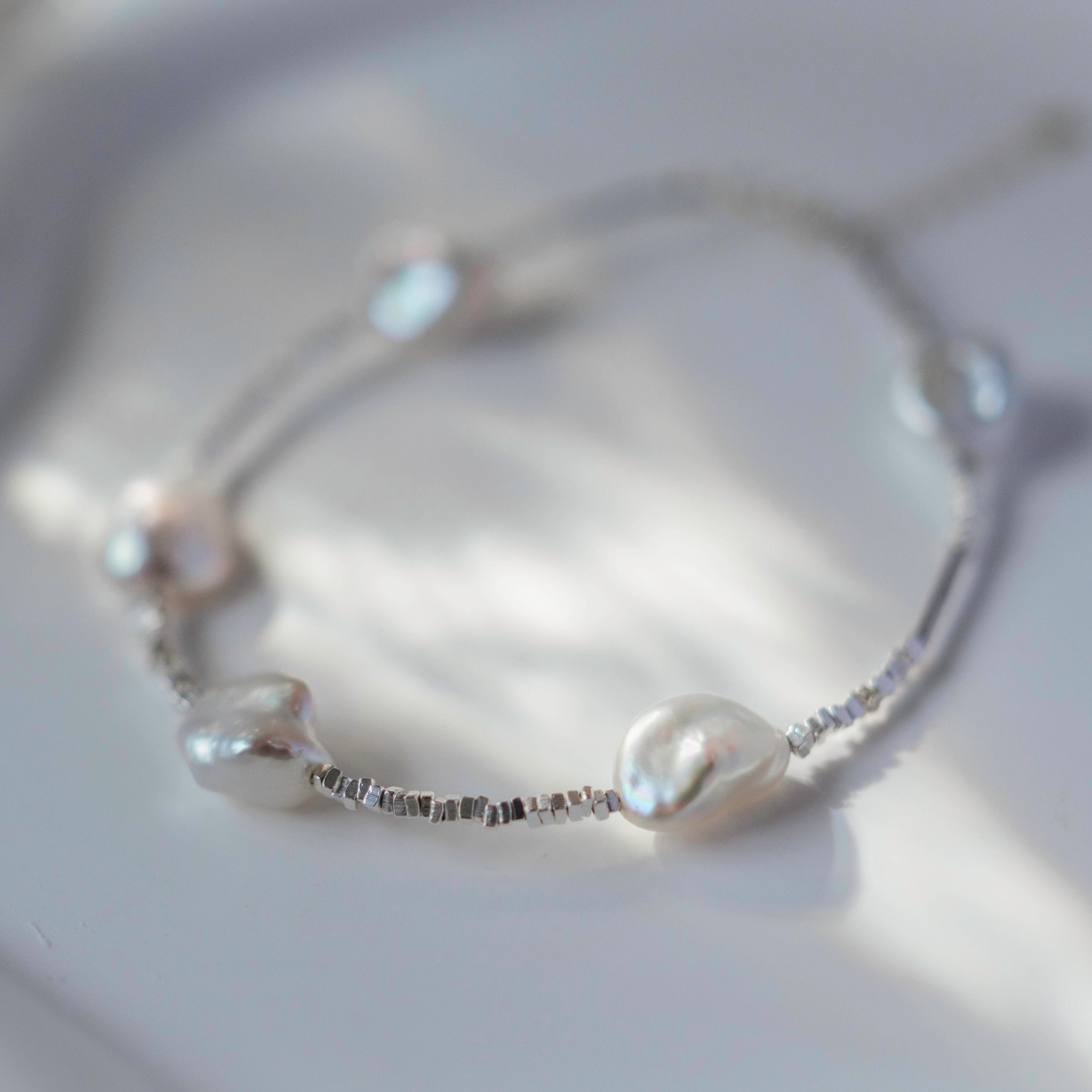 Materials:
- Pearls: Five lustrous Keshi pearls, each about 10mm long.
- Metal: High-quality 925 Sterling Silver for all hardware and detailing.
- Length: The bracelet measures 18.5 cm, featuring an adjustable chain for a customized fit.
Design Highlights: 
This piece is skillfully crafted, showcasing a minimalist yet striking design. The irregularity of the Keshi pearls provides a modern twist on a classic bracelet, complemented by delicate sterling silver accents that add a refined touch.