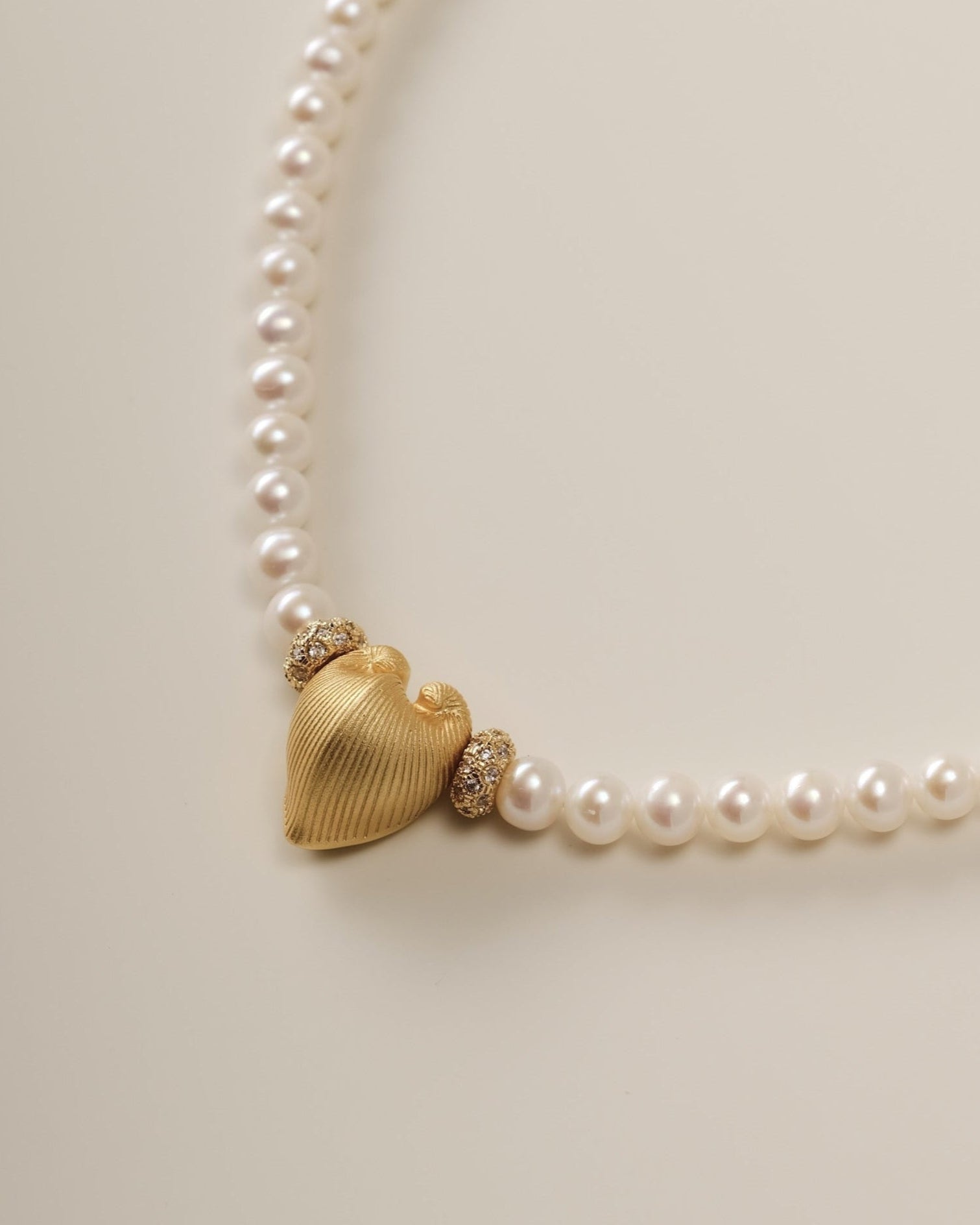 A celestial river of pearls and stardust, the Cœur Brillant Heart Pearl Necklace marries organic serenity with cosmic brilliance. Designed for those who seek elegance with a whisper of rebellion, this piece transforms the delicate balance of strength and softness into a wearable constellation.
Design & Craftsmanship:
Dual-Texture Heart Pendant: The focal 15.6*18.8mm Meiocardia vulgaris heart, crafted in S925 silver and plated in 18k white gold, shifts from rugged, shell-inspired edges to a polished heart si