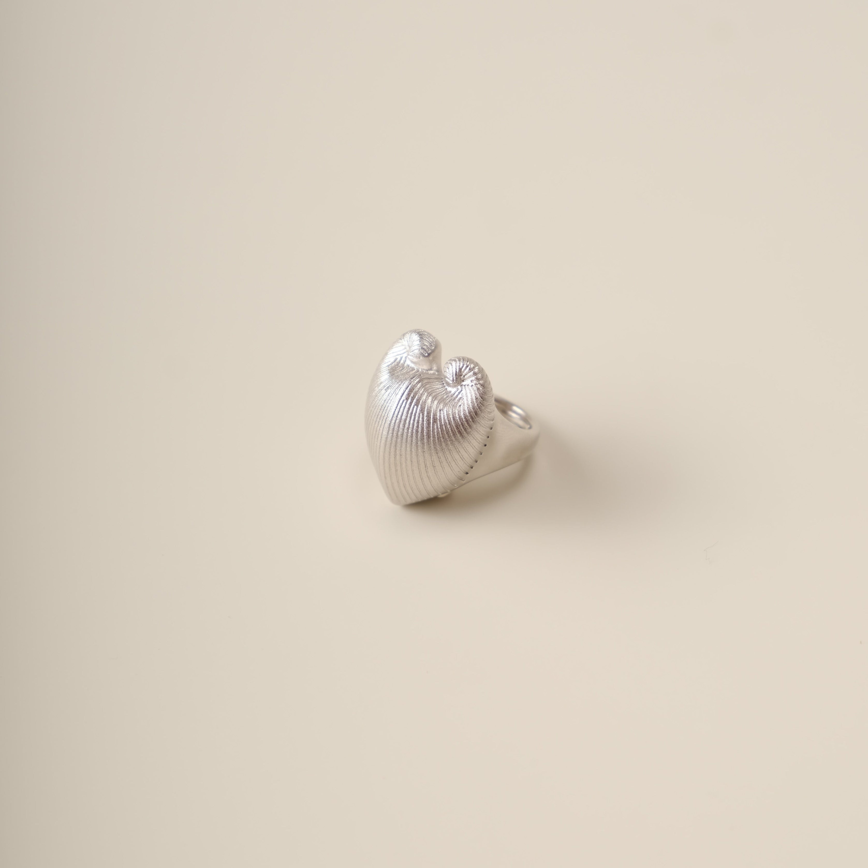 A sculptural ode to nature’s duality, the Meiocardia Vulgaris Heart Ring transforms the organic beauty of a rare marine shell into a bold, wearable statement. Crafted for those who seek depth in simplicity, this ring marries raw texture with refined elegance, embodying the balance of strength and sensitivity.
Design & Craftsmanship:
Dual-Texture Band: The ring’s surface transitions from rugged, shell-inspired ridges to a smooth, polished heart motif at its center—meticulously modeled from a 3D scan of the M
