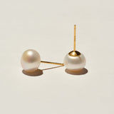 Pair of pearl earrings with gold clasps on a light beige background