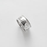 Silver ring with engraved design on a light gray background