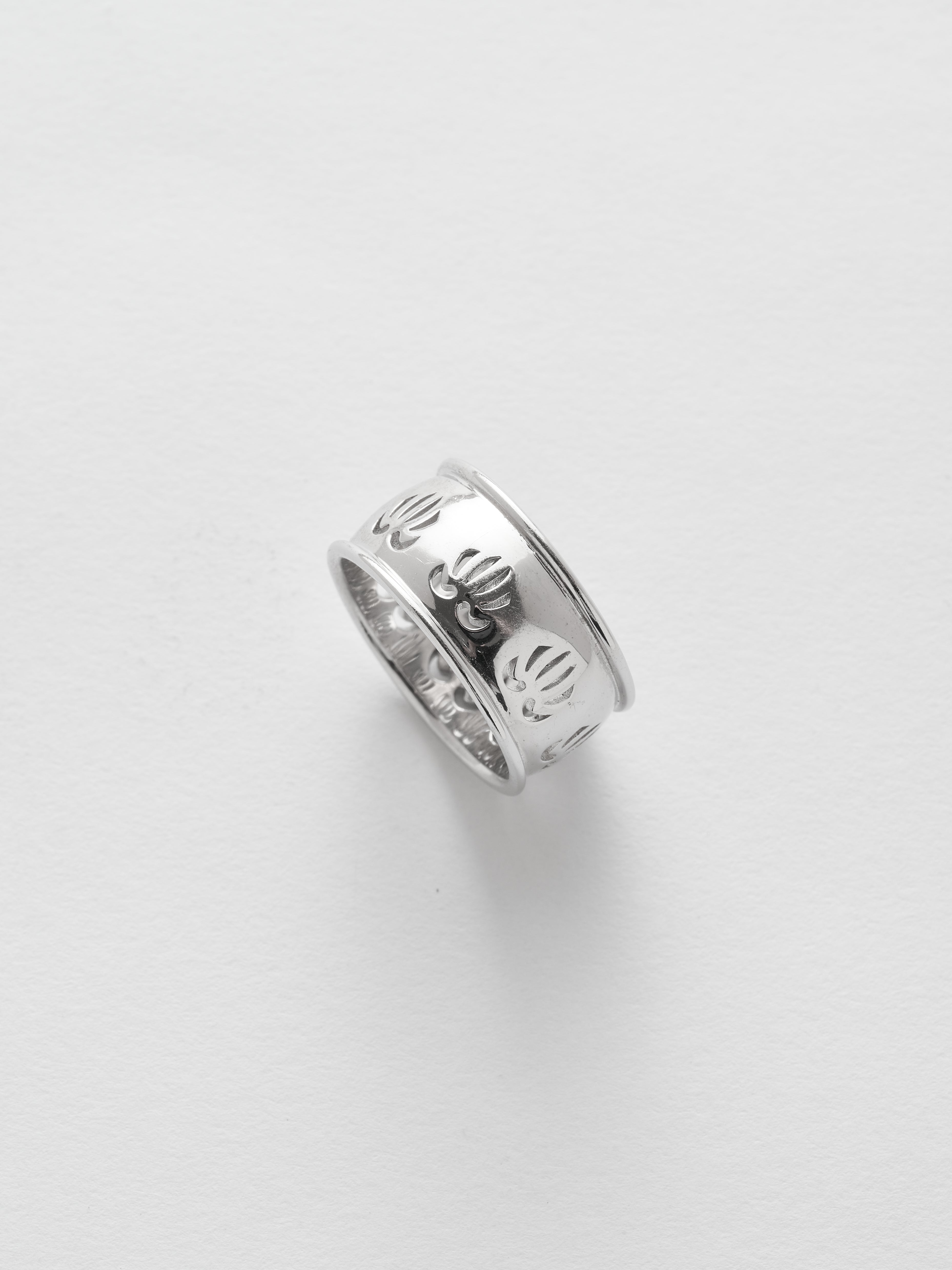 Silver ring with engraved design on a light gray background