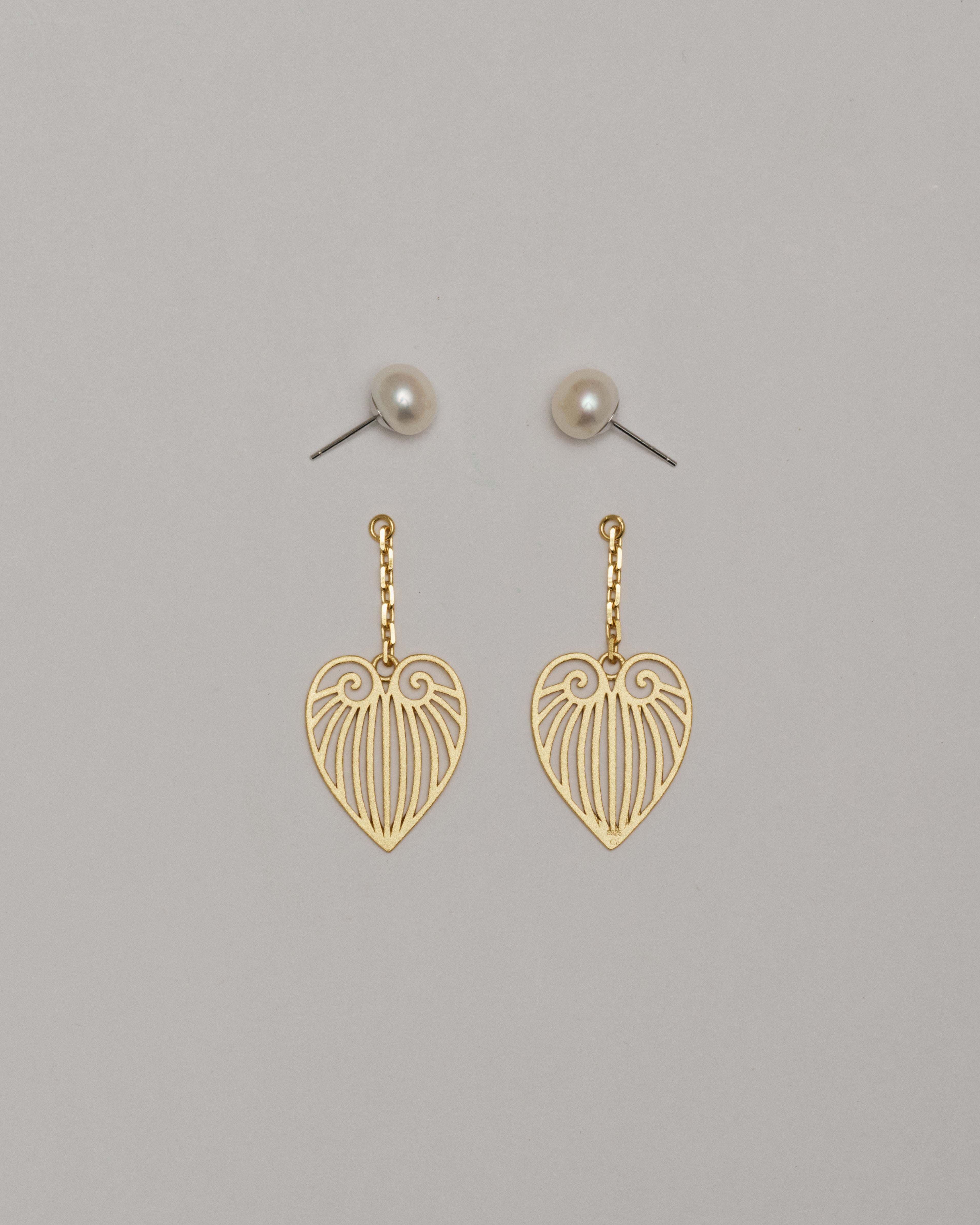 Gold heart-shaped earrings on a gray background