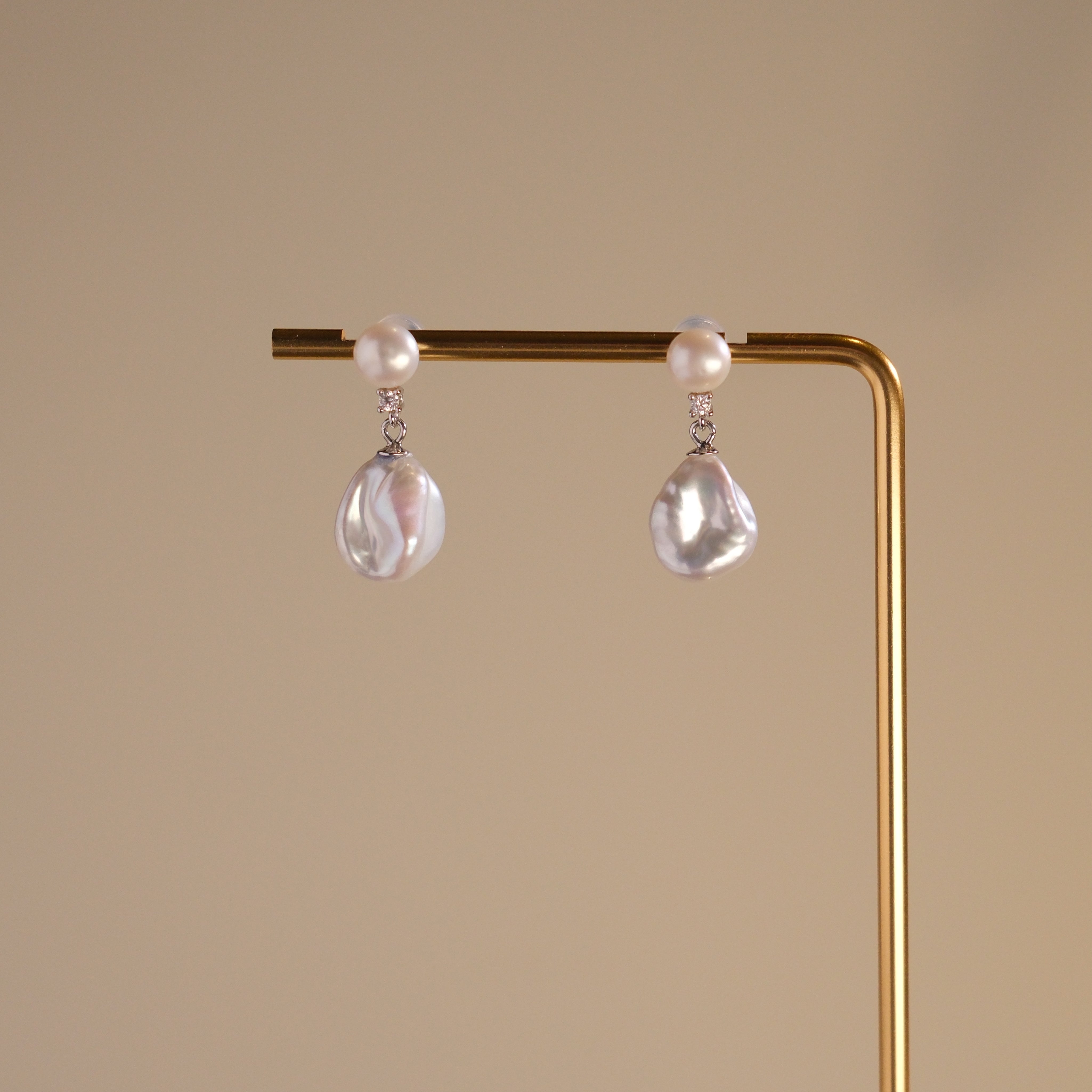 These earrings feature a detachable design that allows you to wear the round pearl with zircon accents for a minimalist look, or add the Keshi pearl for a more dramatic effect. The unique combination of differently shaped pearls with sterling silver and zircon detailing creates a stunning visual contrast, while the versatility of the design makes these earrings a must-have addition to any jewelry collection.
Materials:
- Pearls: One 10mm Keshi pearl and one 6-7mm round pearl on each earring.
- Metal: All co