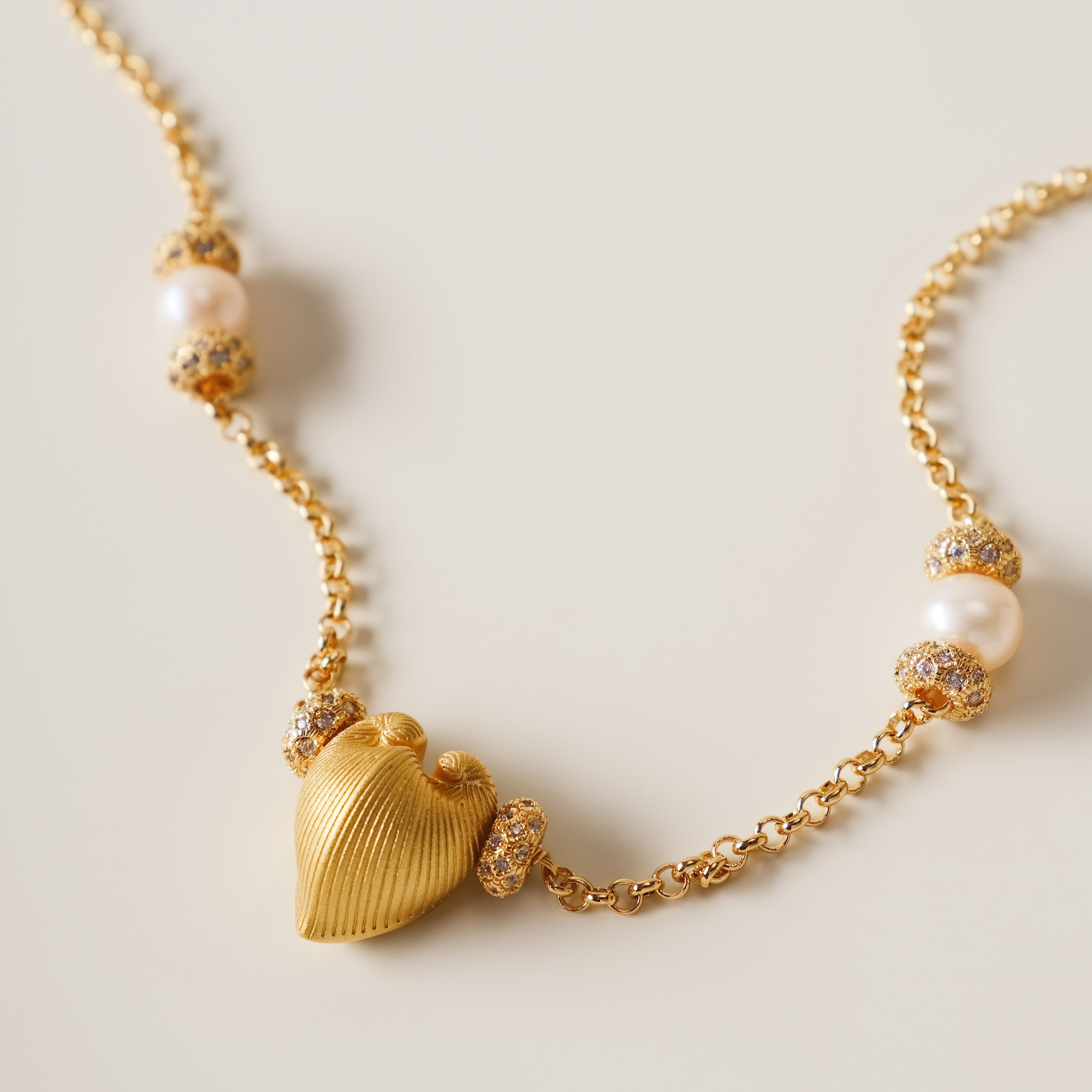 A celestial symphony of love and light, the Meiocardia Vulgaris Heart Necklace is a masterful blend of organic allure and cosmic opulence. Designed for those who seek to wear the stars and the sea, this piece balances bold symbolism with delicate harmony, celebrating the interplay of strength and softness.
Design & Craftsmanship:
Striking Heart Pendant: The centerpiece is a 15.6*18.8mm Meiocardia vulgaris heart bead, cast in lustrous S925 silver and plated with 18k gold. Its dual-textured surface—rugged edg