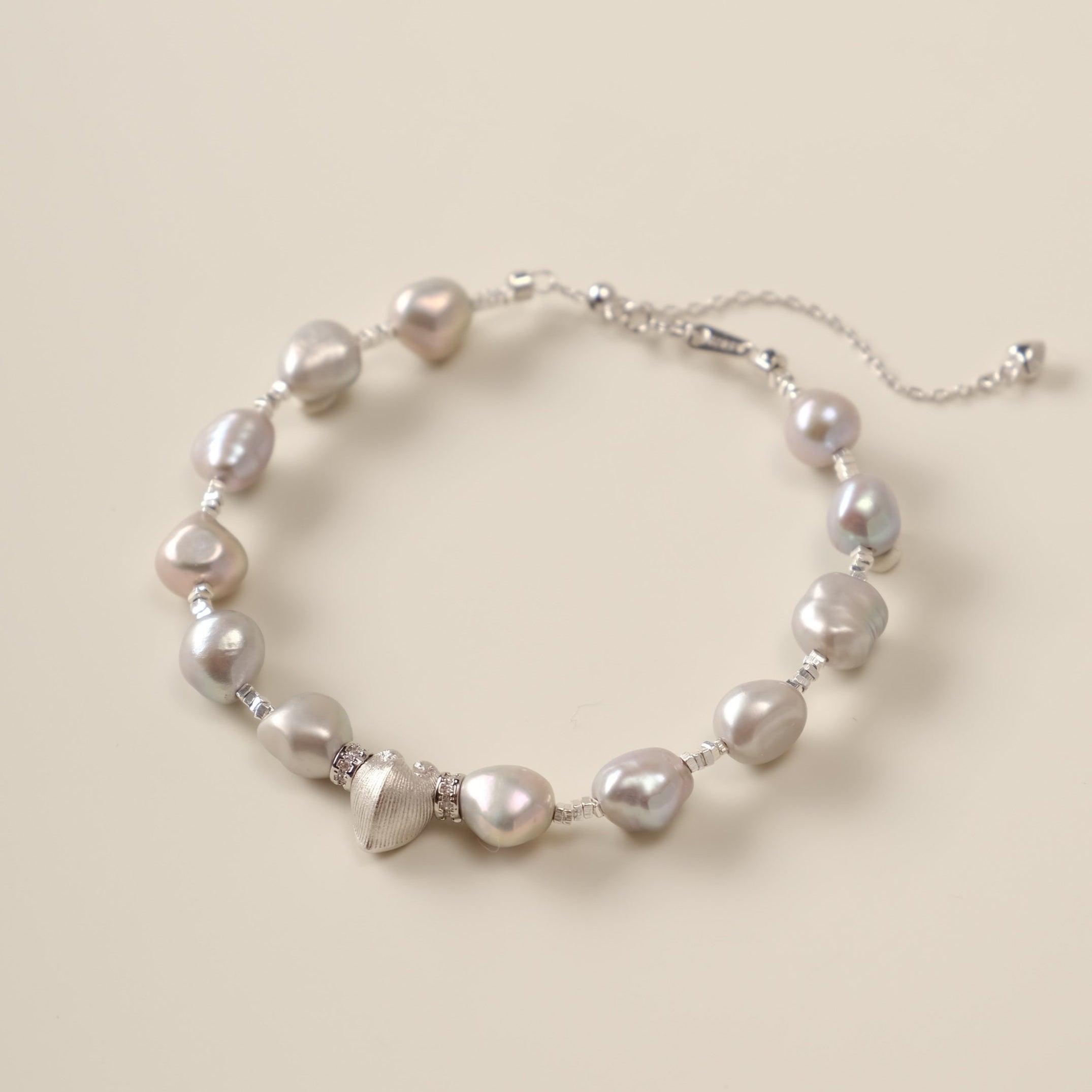 A celestial dance of contrasts, the Meiocardia Vulgaris & Keshi Pearl Bracelet unites the raw magic of ocean-born treasures with the shimmering mystery of the cosmos. Designed for free spirits who embrace imperfection as art, this piece blends a rare heart-shaped shell bead with the organic allure of keshi pearls—a testament to beauty forged in nature’s unpredictable hands.
Design & Craftsmanship:
- Dual-Perspective Heart Charm: The focal 8.0*9.8mm Meiocardia vulgaris bead, cast in hypoallergenic S925 silve