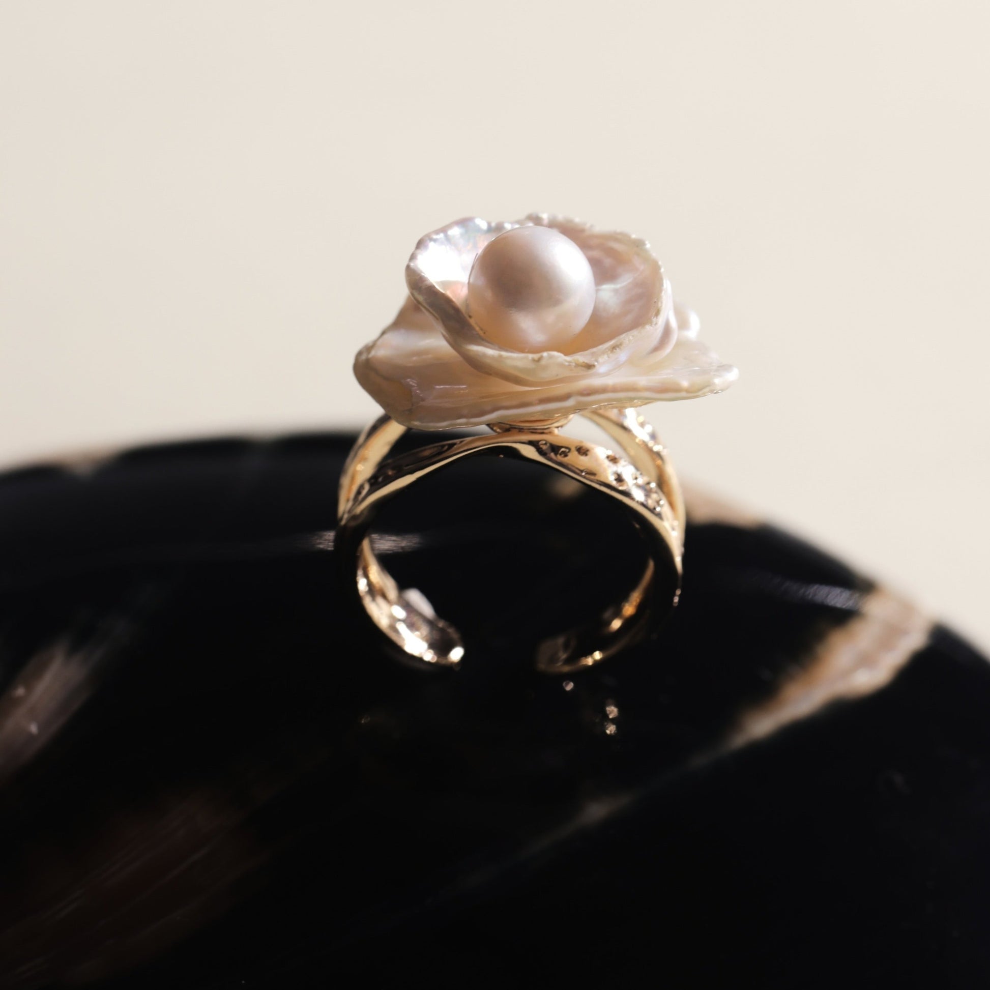 This exquisite floral ring is crafted from rare Keshi petal pearls and topped with a lustrous round freshwater pearl at its center. The natural petal pearls beautifully mimic the delicate petals of a rose, creating a unique and captivating design. The Keshi pearls, known for their irregular shape and stunning luster, make this ring a one-of-a-kind piece that’s perfect for any occasion.Ring is made using high-quality Keshi petal pearls and a freshwater pearl, set on an 18k gold-filled adjustable band