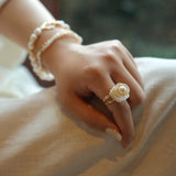 This exquisite floral ring is crafted from rare Keshi petal pearls and topped with a lustrous round freshwater pearl at its center. The natural petal pearls beautifully mimic the delicate petals of a rose, creating a unique and captivating design. The Keshi pearls, known for their irregular shape and stunning luster, make this ring a one-of-a-kind piece that’s perfect for any occasion.Ring is made using high-quality Keshi petal pearls and a freshwater pearl, set on an 18k gold-filled adjustable band