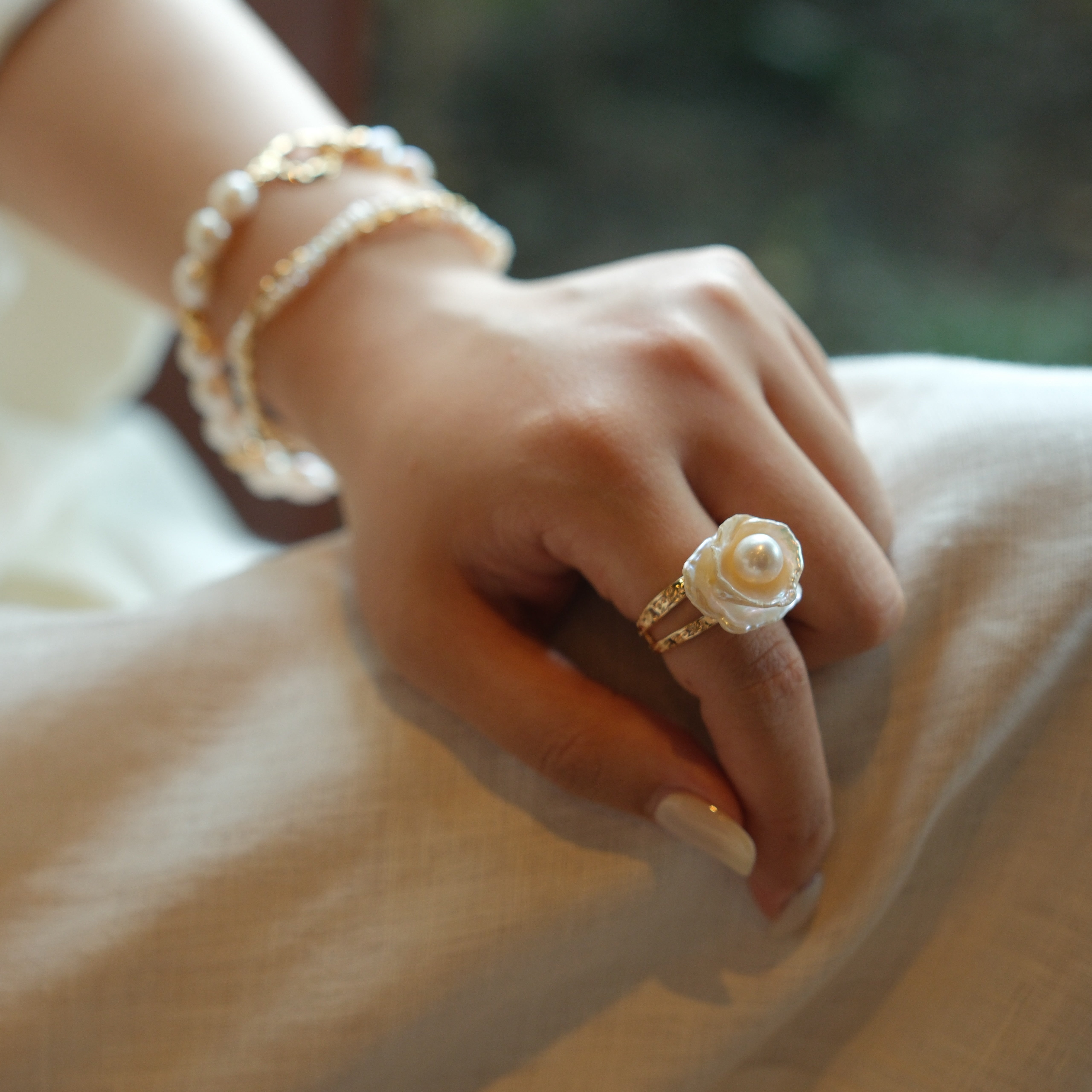This exquisite floral ring is crafted from rare Keshi petal pearls and topped with a lustrous round freshwater pearl at its center. The natural petal pearls beautifully mimic the delicate petals of a rose, creating a unique and captivating design. The Keshi pearls, known for their irregular shape and stunning luster, make this ring a one-of-a-kind piece that’s perfect for any occasion.Ring is made using high-quality Keshi petal pearls and a freshwater pearl, set on an 18k gold-filled adjustable band